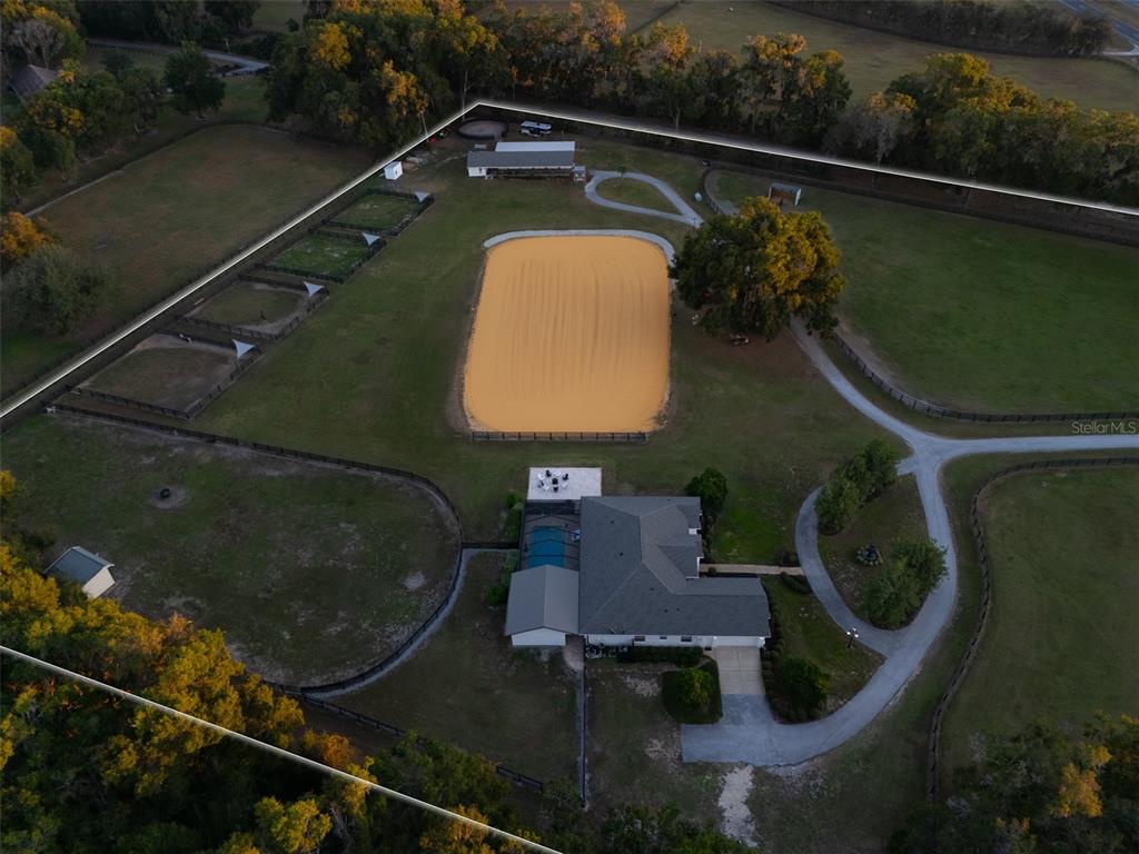 An aerial view shows a house with a pool, a riding arena, and fenced pastures — 14335 N US HIGHWAY 441, CITRA, FL