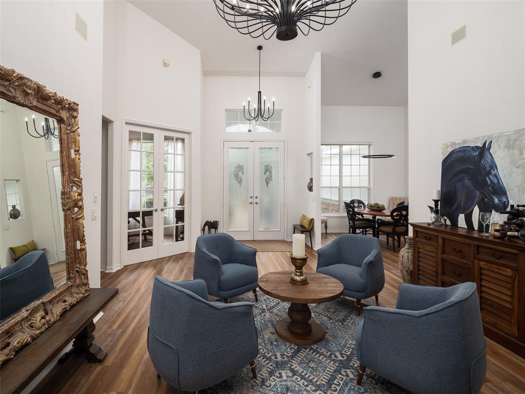 A high-ceilinged foyer features four blue armchairs, a round wooden table, and a large mirror — 14335 N US HIGHWAY 441, CITRA, FL