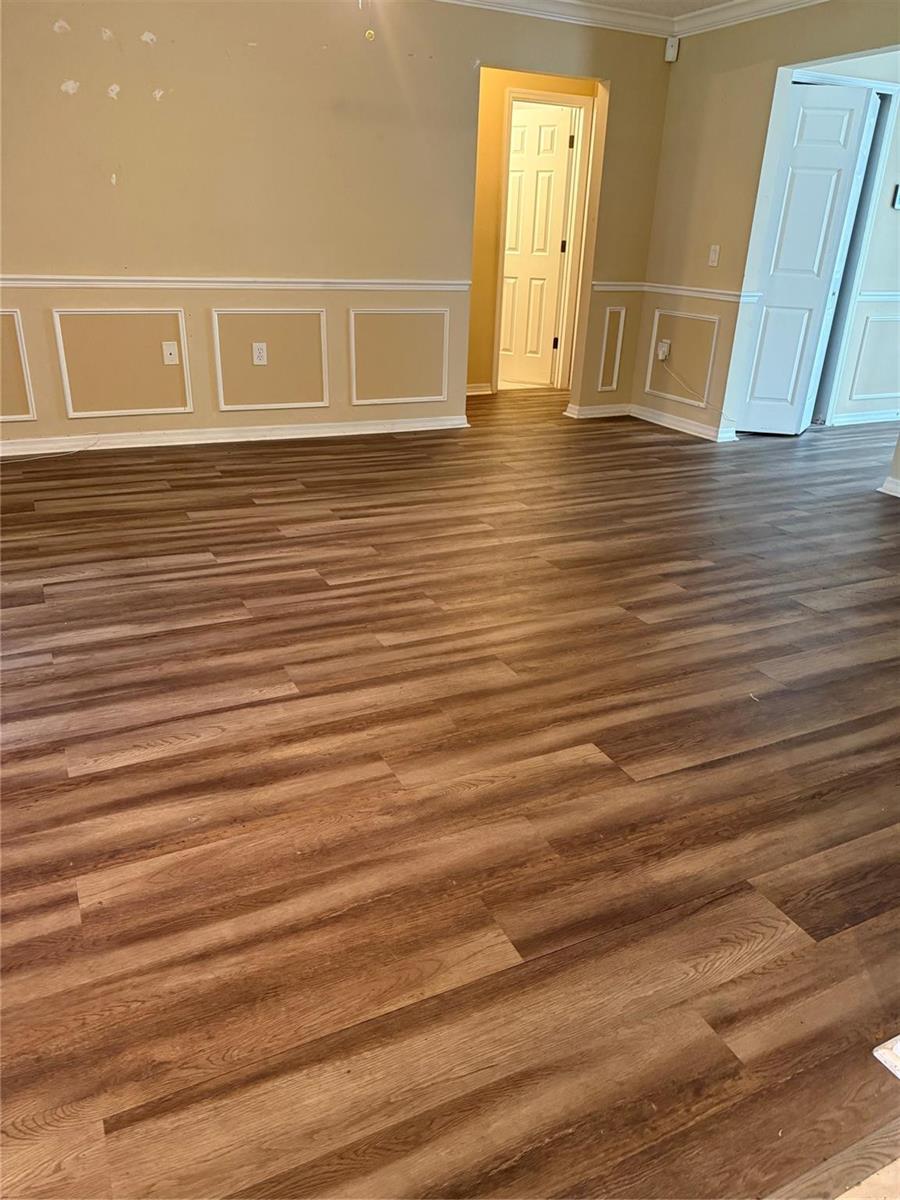 A room with wood-look flooring, beige walls, and white wainscoting trim — 7821 Shellbark Drive, Orlando FL 32818, ORLANDO, FL