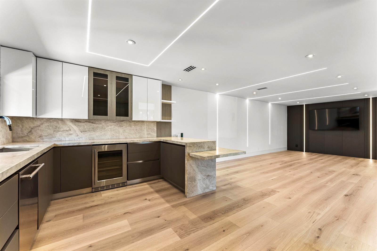 A modern kitchen features two-tone cabinetry, marble countertops, and integrated lighting in an open space — 1692 S Ocean Boulevard, Delray Beach FL 33483, DELRAY BEACH, FL