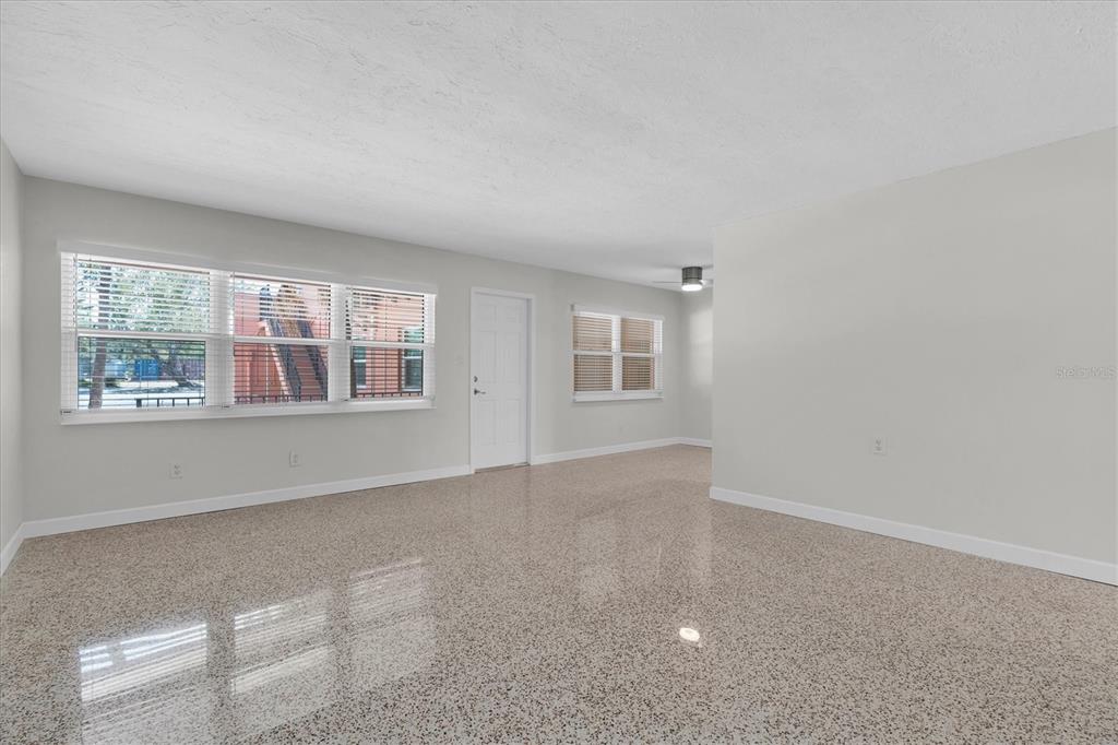 An empty room with light gray walls, white trim, and speckled terrazzo flooring — 121 46TH AVENUE UNIT 1G, ST PETE BEACH, FL