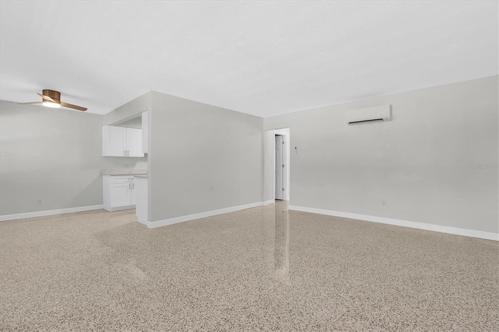 An open living area features light gray walls, a ceiling fan, and speckled flooring — 121 46TH AVENUE UNIT 1G, ST PETE BEACH, FL