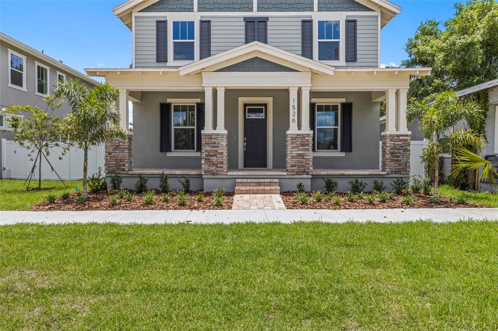 A two-story house with a covered front porch, stone columns, and gray siding — 1526 W ARCH STREET, TAMPA, FL