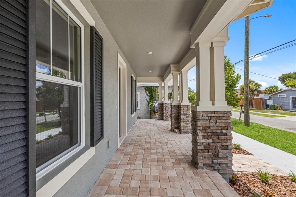 A covered front porch features stone-based columns, a paver floor, and dark window shutters — 1526 W ARCH STREET, TAMPA, FL