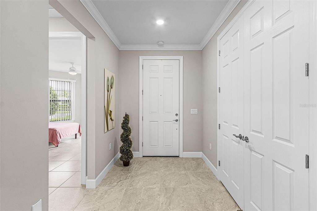 A bright entryway features light-colored tile flooring, a white front door, and a closet door — 12437 GOLDEN SAGE DRIVE, SARASOTA, FL
