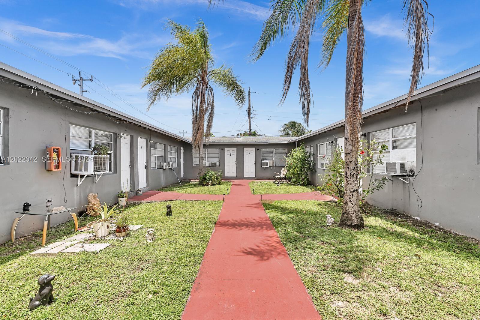 A courtyard with a red walkway sits between two gray, single-story apartment buildings — 5685 Flagler St # 2, Hollywood FL 33023, HOLLYWOOD, FL