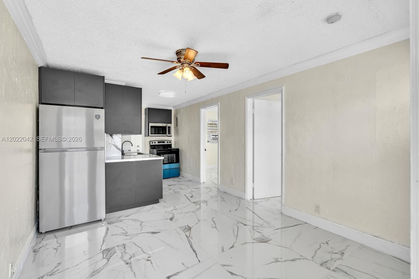 A kitchen features dark gray cabinets, stainless steel appliances, and white marble-patterned tile flooring — 5685 Flagler St # 2, Hollywood FL 33023, HOLLYWOOD, FL