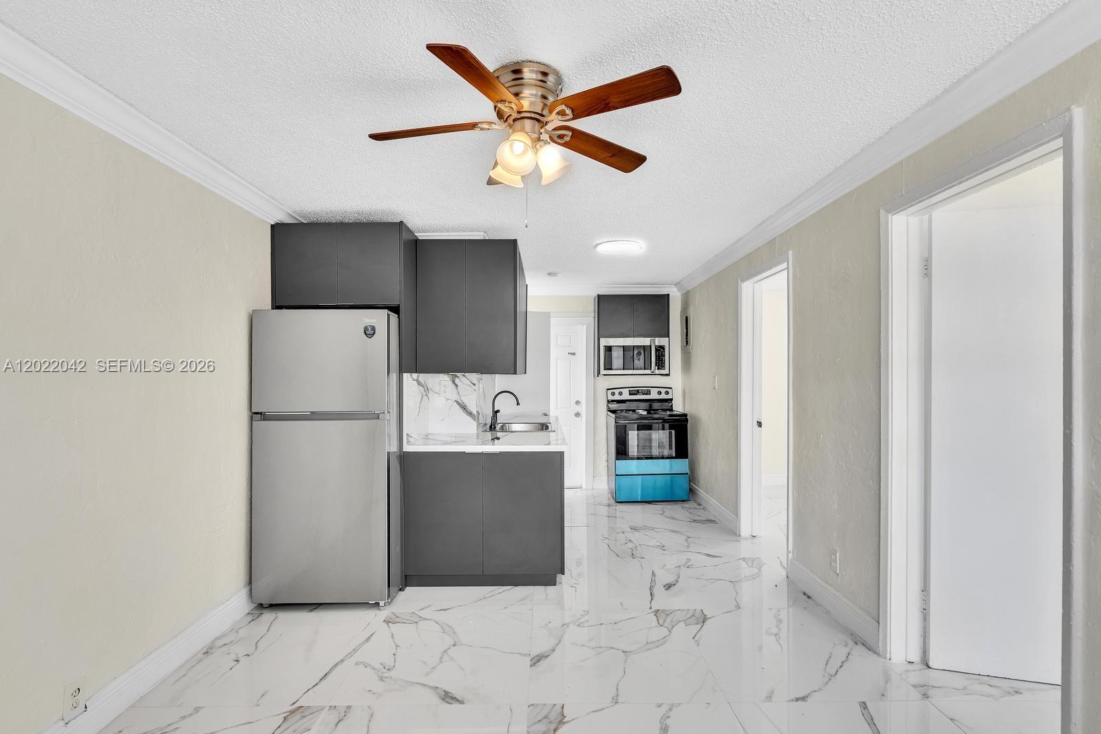 A kitchen features dark gray cabinets, stainless steel appliances, and white marble-patterned tile flooring — 5685 Flagler St # 2, Hollywood FL 33023, HOLLYWOOD, FL