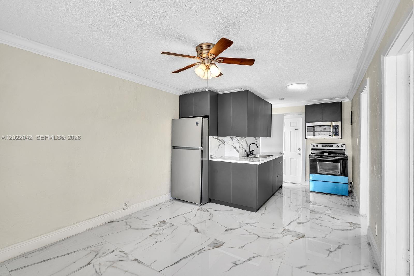 A kitchen features dark gray cabinets, stainless steel appliances, and white marble-patterned tile flooring — 5685 Flagler St # 2, Hollywood FL 33023, HOLLYWOOD, FL