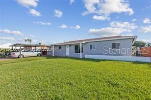 A single-story house with a gray exterior, a metal carport, and a large grassy yard — 10471 SW 141 STREET, MIAMI, FL