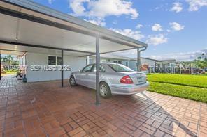 A silver sedan is parked under a covered carport in front of a house — 10471 SW 141 STREET, MIAMI, FL