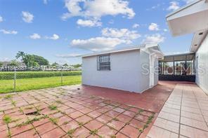 A backyard patio with red pavers leads to a small detached shed and a screened porch — 10471 SW 141 STREET, MIAMI, FL