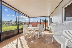 A screened-in patio features a brick-paver floor, white plastic furniture, and views of a grassy yard — 10471 SW 141 STREET, MIAMI, FL