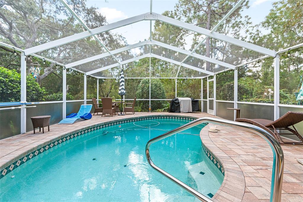 A screened-in pool area features a paver deck, patio furniture, and a metal handrail — 4 IPOMOEA COURT, HOMOSASSA, FL