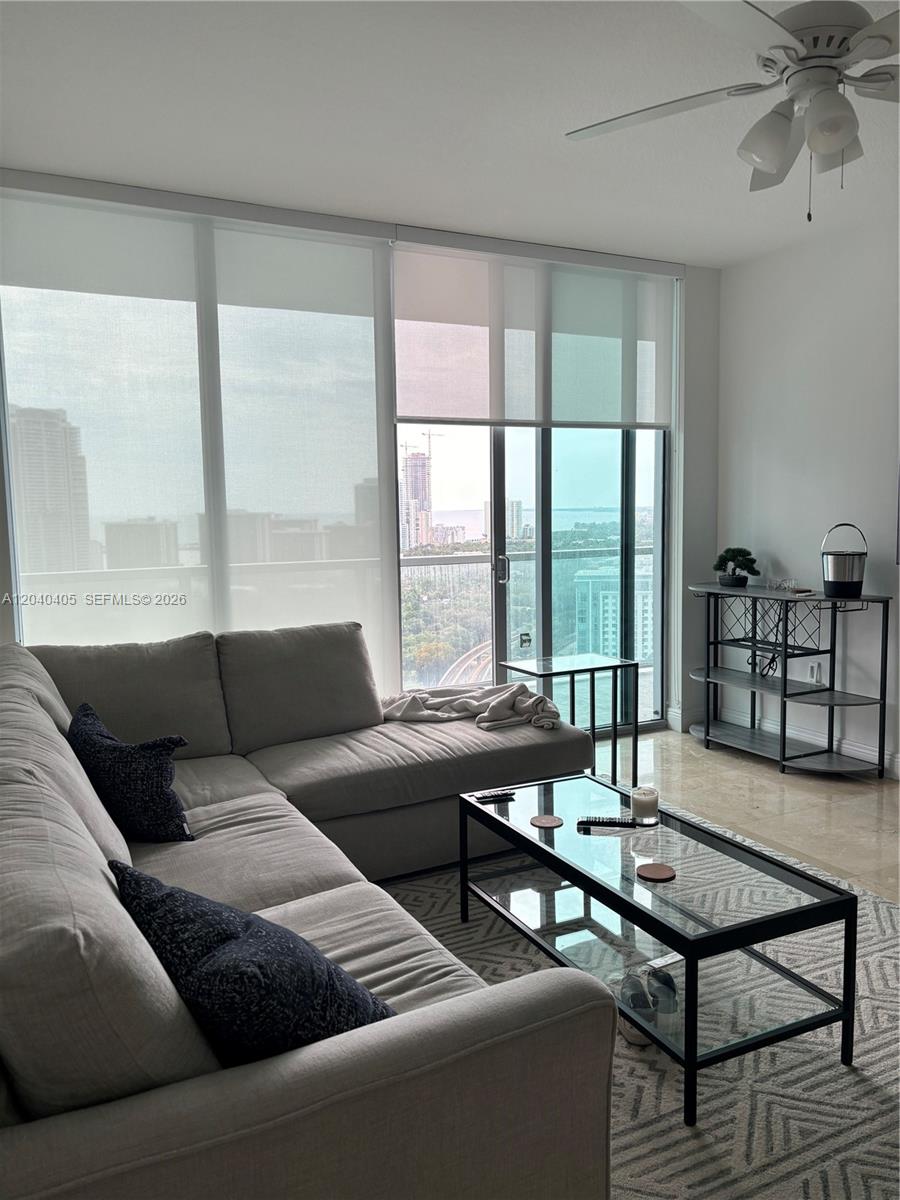 A living room features a gray sectional sofa, a glass coffee table, and floor-to-ceiling windows — 79 SW 12th St, Miami FL 33130, MIAMI, FL