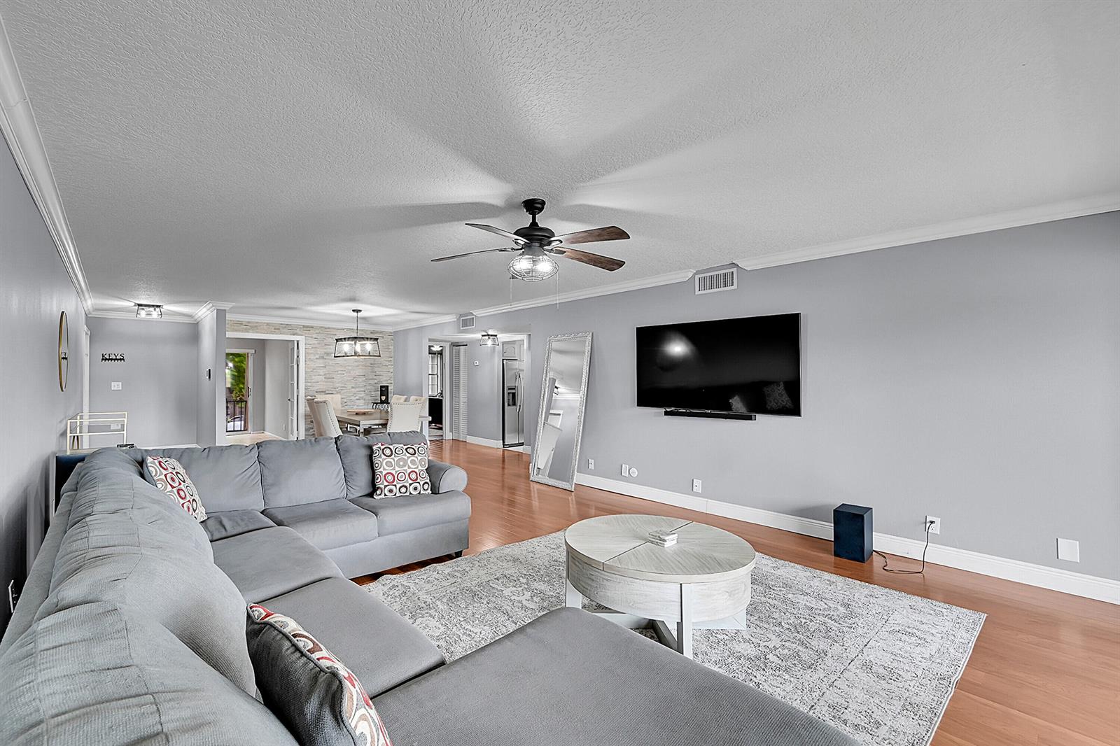 A living room features a grey sectional sofa, a round coffee table, and a wall-mounted television — 3630 Citrus Trace # 4, Davie FL 33328, DAVIE, FL