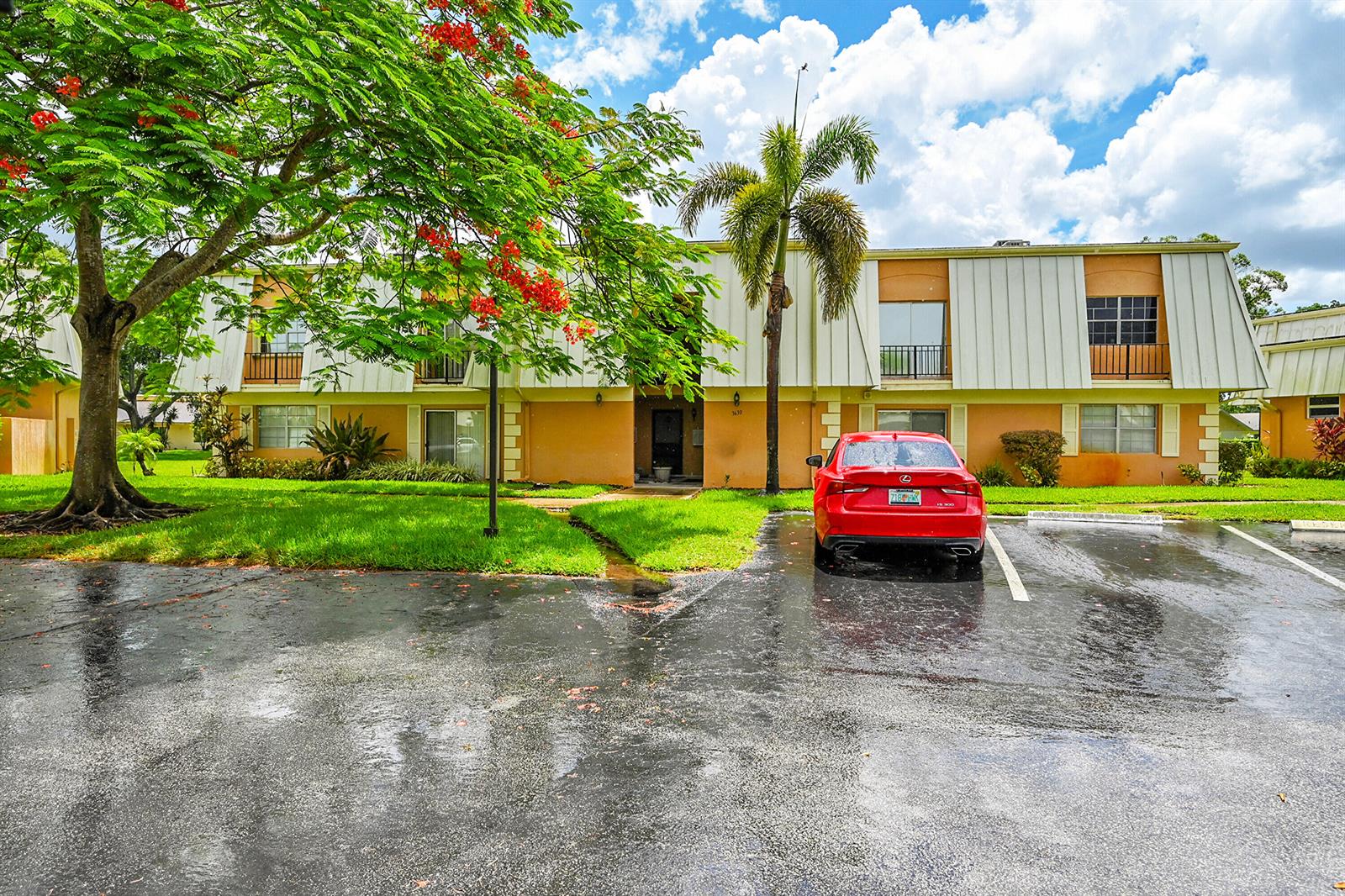 A red sedan is parked in front of a two-story apartment building with palm trees — 3630 Citrus Trace # 4, Davie FL 33328, DAVIE, FL