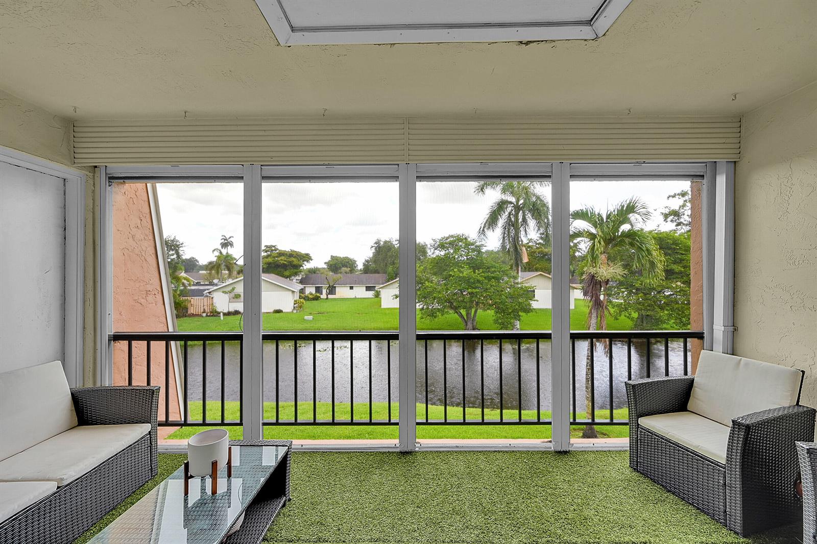 A screened-in balcony with artificial turf flooring overlooks a pond and residential neighborhood — 3630 Citrus Trace # 4, Davie FL 33328, DAVIE, FL