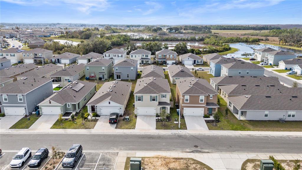 An aerial view shows a suburban neighborhood with rows of houses and a nearby pond — 2630 ANGEL FALLS DRIVE, DAVENPORT, FL