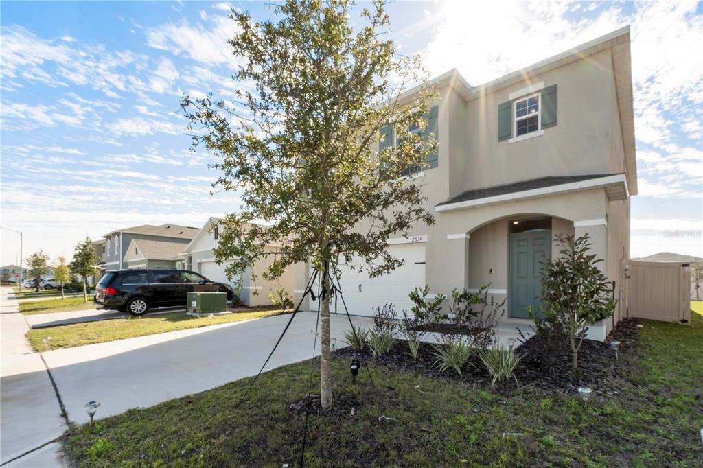 A two-story suburban house with a beige stucco exterior, a garage, and a front yard — 2630 ANGEL FALLS DRIVE, DAVENPORT, FL