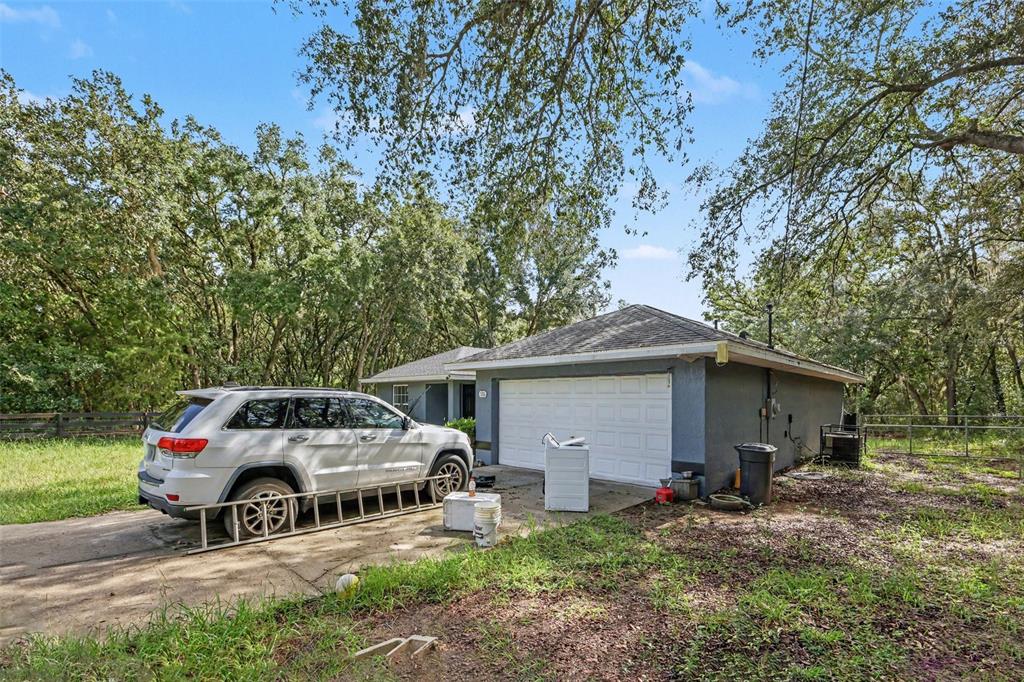 A white SUV is parked on a concrete driveway in front of a detached garage — 135 FISHER WAY TRAIL, OCKLAWAHA, FL
