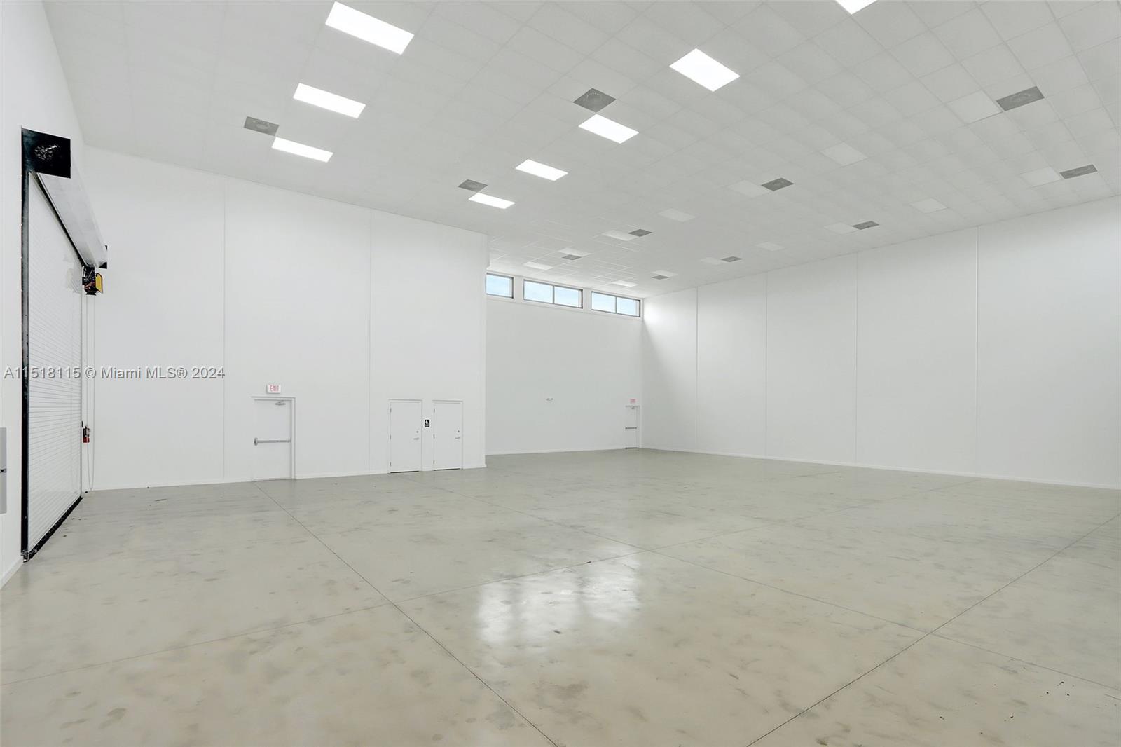 An empty, white-walled industrial warehouse space features a concrete floor and recessed ceiling lighting — 235 NE 67th St, Miami FL 33138, MIAMI, FL
