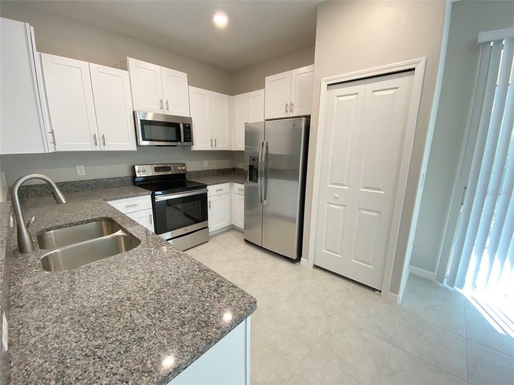 A kitchen with white cabinets, stainless steel appliances, and granite countertops — 8533 REEDVILLE STREET, NEW PORT RICHEY, FL
