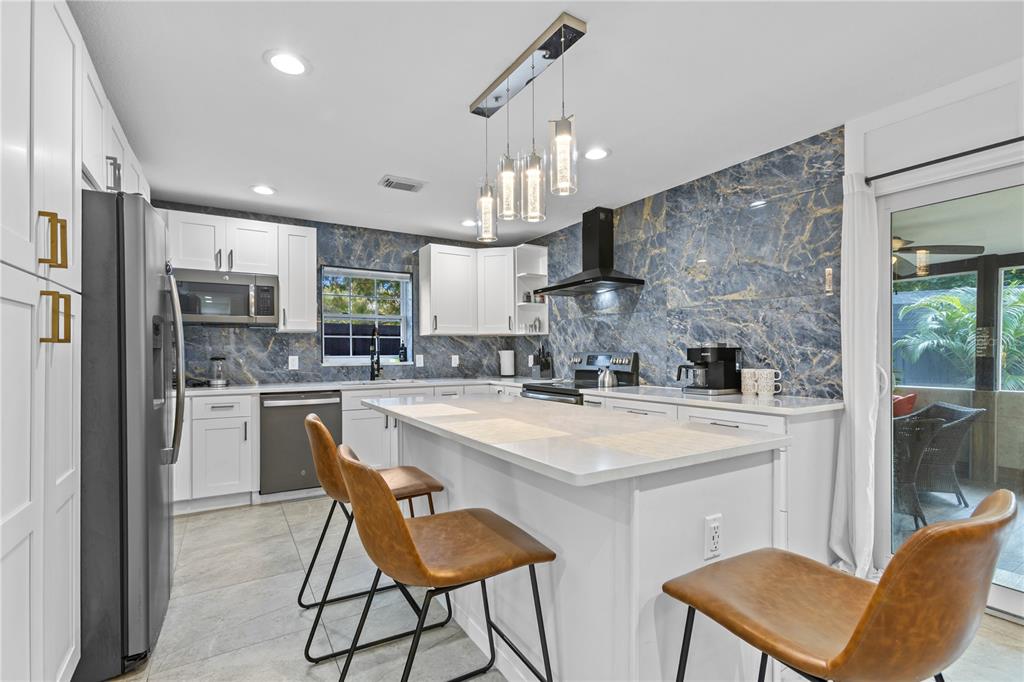 A modern kitchen features white cabinets, a blue marble backsplash, and a central island — 6822 S WALL STREET, TAMPA, FL