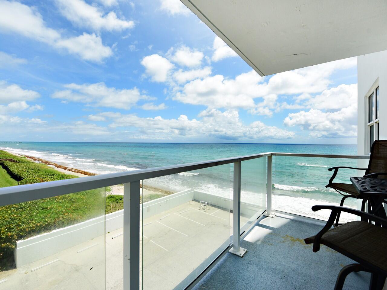 A balcony with glass railings overlooks the ocean and a parking lot below — 3450 S Ocean Boulevard # 308, Palm Beach FL 33480, PALM BEACH, FL