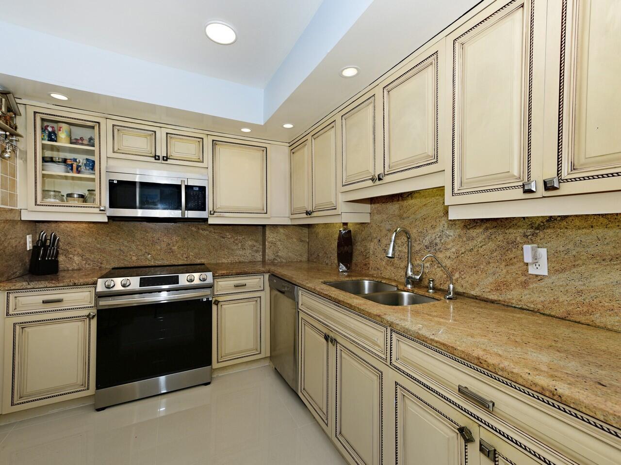 A kitchen features cream-colored cabinets, granite countertops, stainless steel appliances, and tile flooring — 3450 S Ocean Boulevard # 308, Palm Beach FL 33480, PALM BEACH, FL