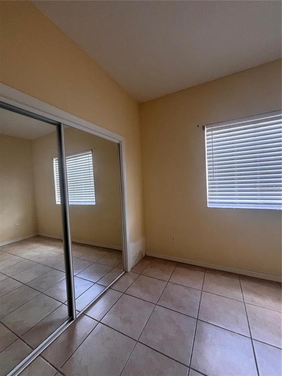 A room with tiled floors, a mirrored closet, and a window with white blinds — 21102 INDIAN CREEK DRIVE, POINCIANA, FL