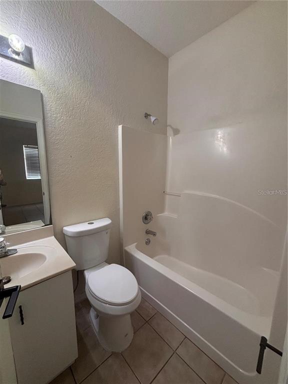 A bathroom features a white toilet, a vanity with a sink, and a shower-tub combination — 21102 INDIAN CREEK DRIVE, POINCIANA, FL