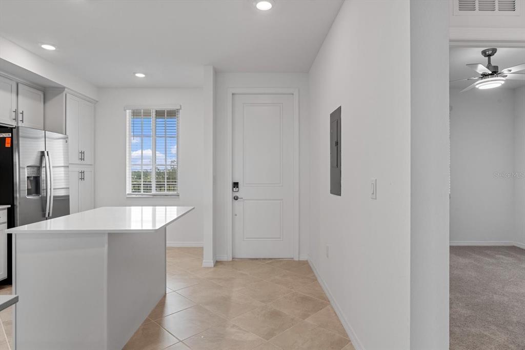 A kitchen with white cabinets, a quartz island, tile flooring, and a door to outside — 12180 WELLEN GOLF STREET UNIT 305, VENICE, FL