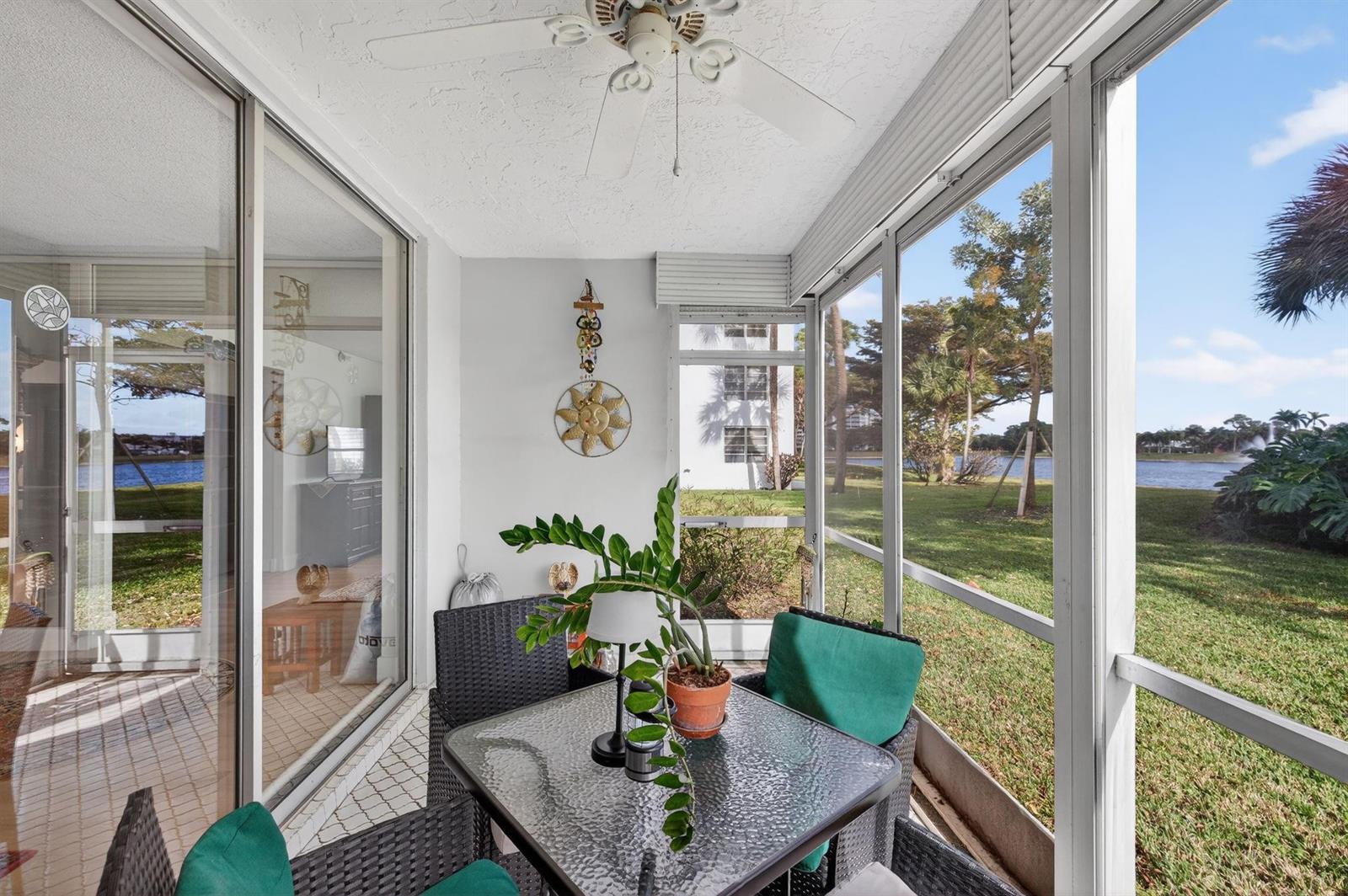 A screened-in patio features a glass-top table, wicker chairs, and views of a lake — 3200 N Course Lane # 116, Pompano Beach FL 33069, POMPANO BEACH, FL