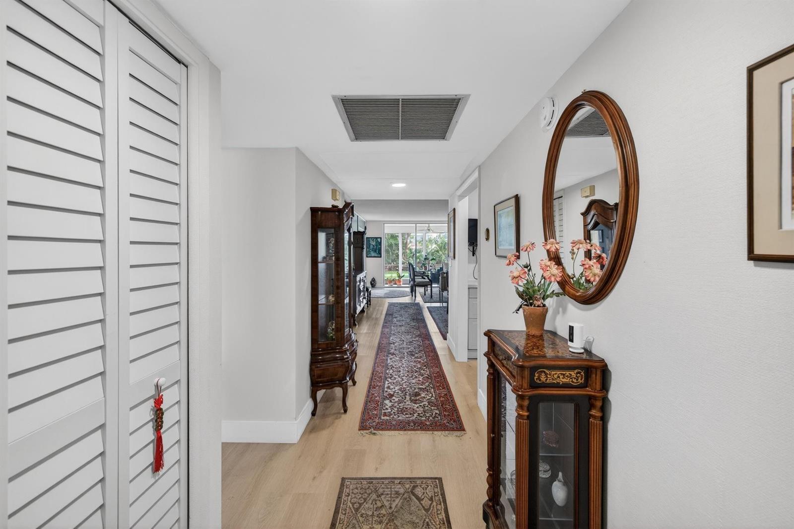 A hallway with light wood flooring, a long runner rug, and traditional wooden furniture — 3200 N Course Lane # 116, Pompano Beach FL 33069, POMPANO BEACH, FL