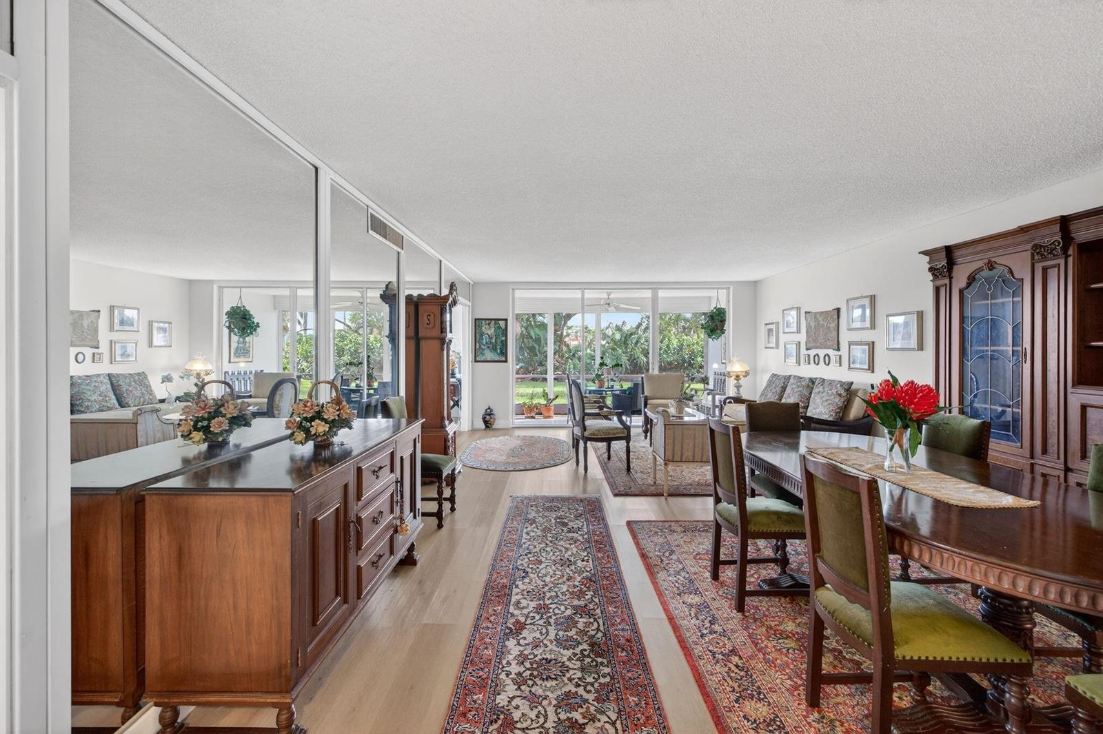 A dining and living area features wood furniture, patterned rugs, and a large mirrored wall — 3200 N Course Lane # 116, Pompano Beach FL 33069, POMPANO BEACH, FL