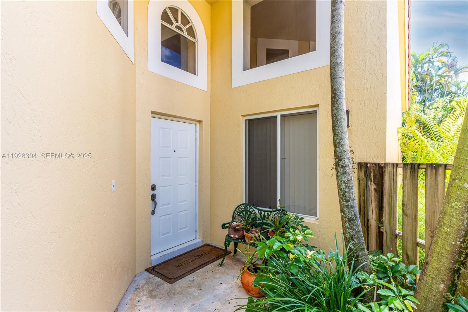An exterior view of a home entrance featuring a white door, arched window, and bench — 10132 NW 4th St, Plantation FL 33324, PLANTATION, FL