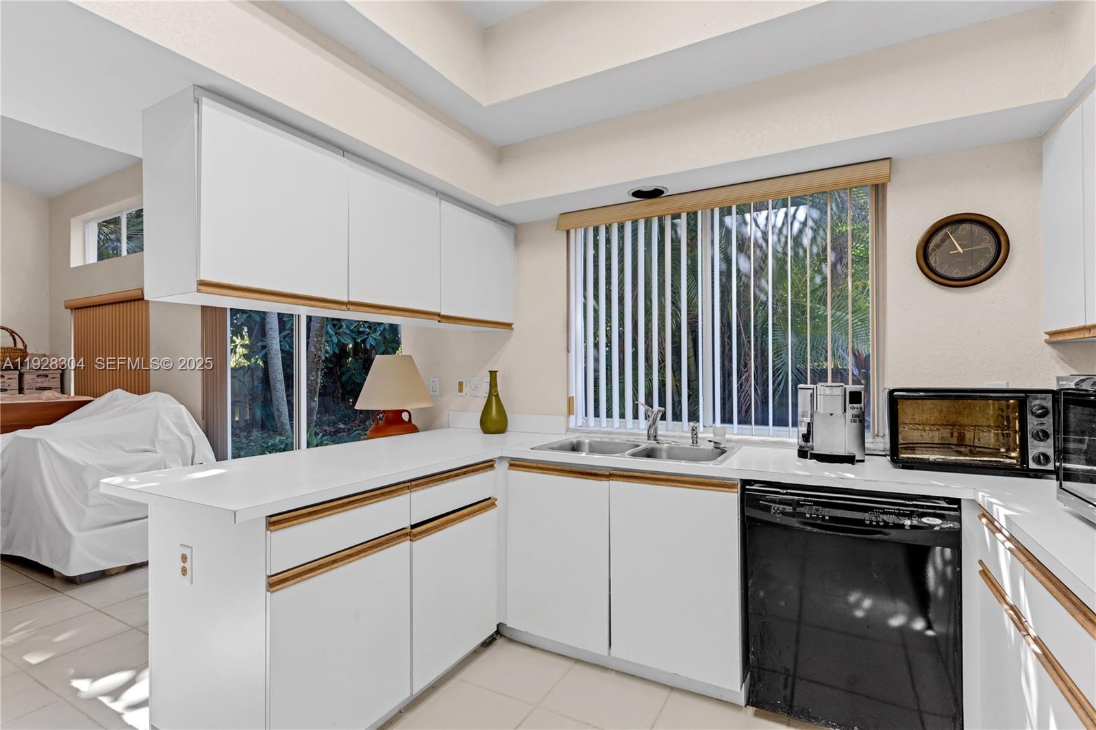 A kitchen features white cabinets with wood trim, a double sink, and a black dishwasher — 10132 NW 4th St, Plantation FL 33324, PLANTATION, FL