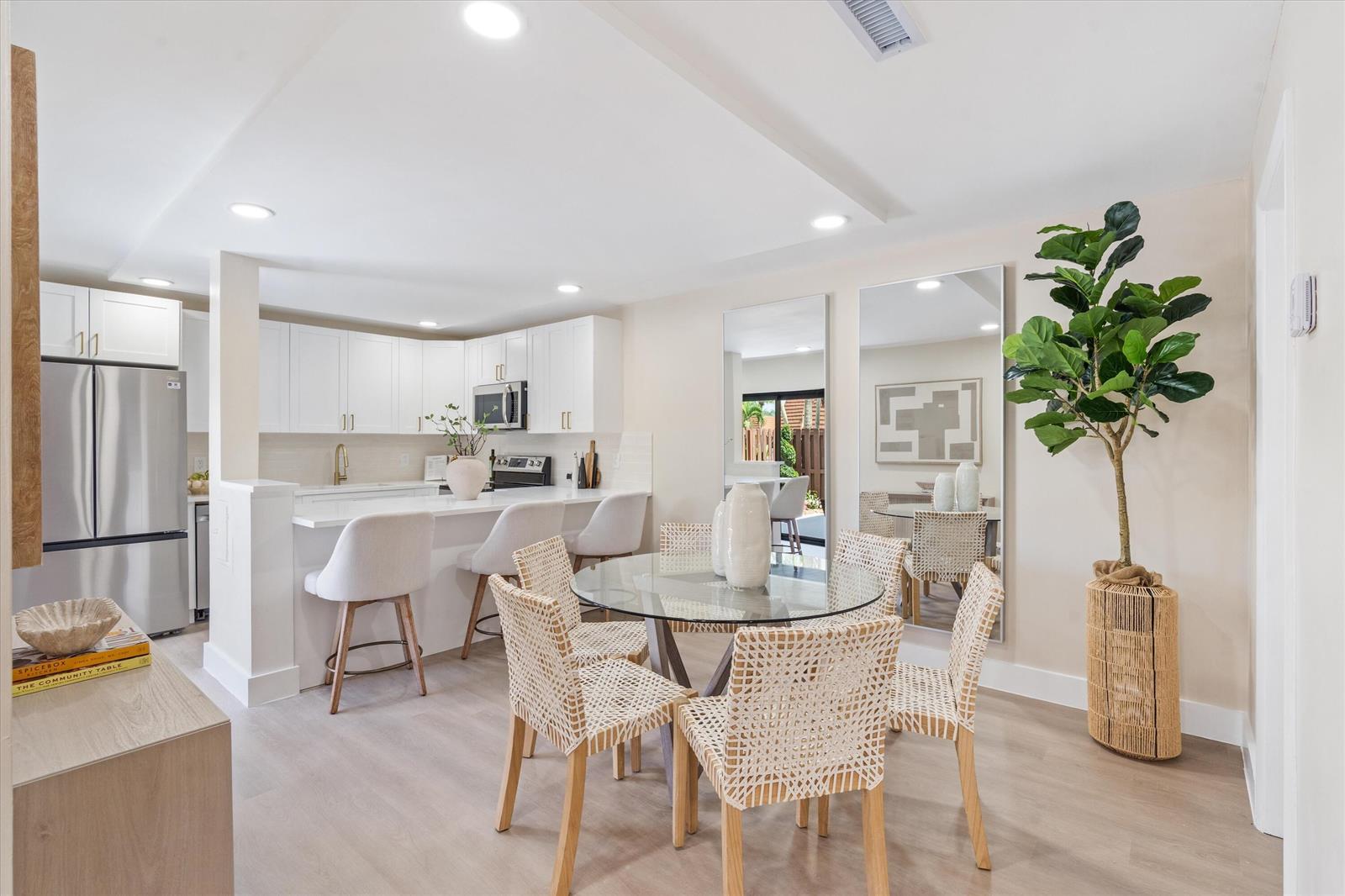 A kitchen with white cabinets and a breakfast bar next to a glass dining table — 825 Center Street # 49d, Jupiter FL 33458, JUPITER, FL