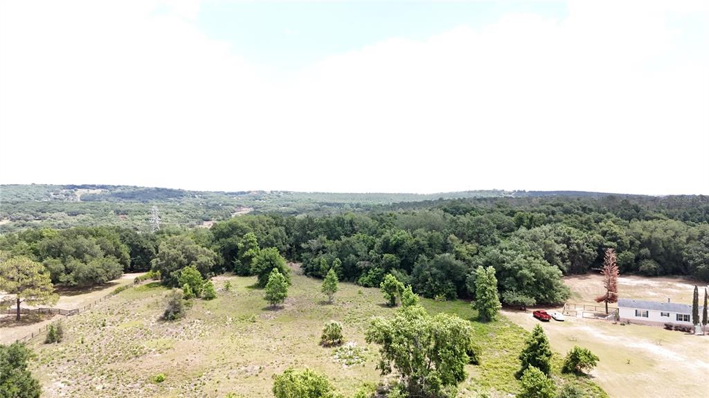 An aerial view shows a rural property with a house, scattered trees, and rolling hills — SONOMA RIDGE ROAD, CLERMONT, FL