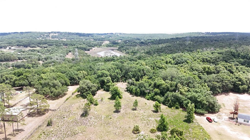 An aerial view shows a grassy lot with scattered trees, a small pond, and nearby houses — SONOMA RIDGE ROAD, CLERMONT, FL