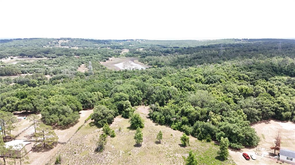 An aerial view shows a large, wooded lot with a small pond and two buildings — SONOMA RIDGE ROAD, CLERMONT, FL