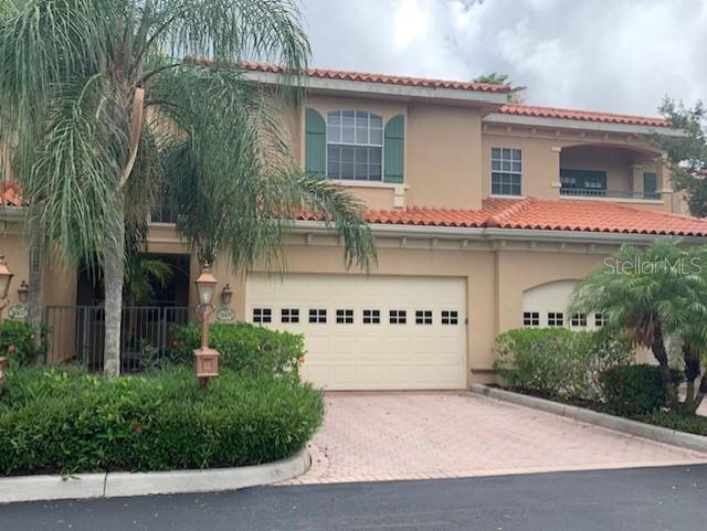 A two-story stucco townhouse with a tile roof, a two-car garage, and palm trees — 3625 SQUARE WEST LANE UNIT 4, SARASOTA, FL