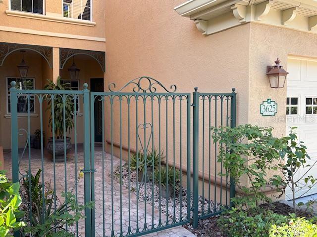 A green metal gate leads to a paved courtyard entrance of a stucco home — 3625 SQUARE WEST LANE UNIT 4, SARASOTA, FL