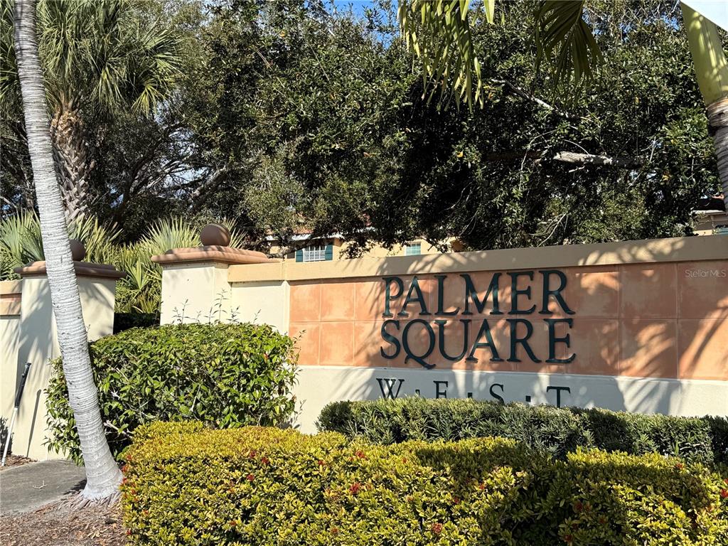 A beige stucco monument sign for Palmer Square West stands in front of lush landscaping — 3625 SQUARE WEST LANE UNIT 4, SARASOTA, FL