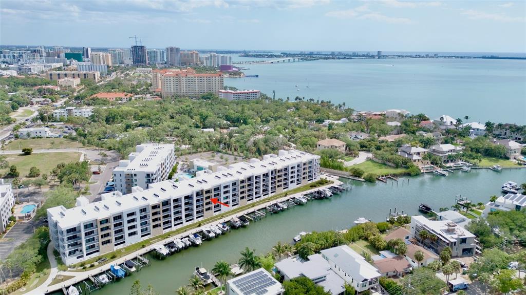 An aerial view shows a multi-story apartment building with a marina along a canal — 1709 N TAMIAMI TRAIL UNIT 416, SARASOTA, FL