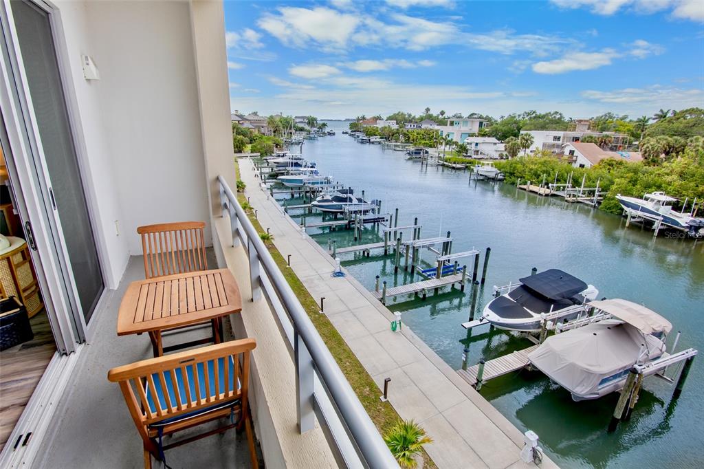 A balcony with a wooden table and chairs overlooks a canal filled with docked boats — 1709 N TAMIAMI TRAIL UNIT 416, SARASOTA, FL