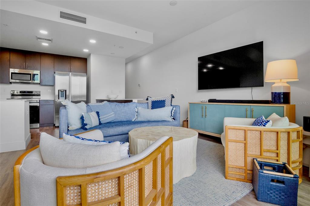 A living room features a blue sofa, rattan chairs, a coffee table, and a television — 1709 N TAMIAMI TRAIL UNIT 416, SARASOTA, FL