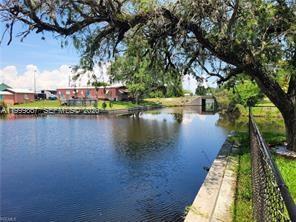 A canal view showing a grassy bank, a chain-link fence, and a mobile home nearby — 1104 Gulf St, Moore Haven FL 33471, MOORE HAVEN, FL