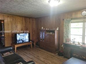 A living room features wood-paneled walls, wood-look flooring, a television on a stand, and cabinetry — 1104 Gulf St, Moore Haven FL 33471, MOORE HAVEN, FL